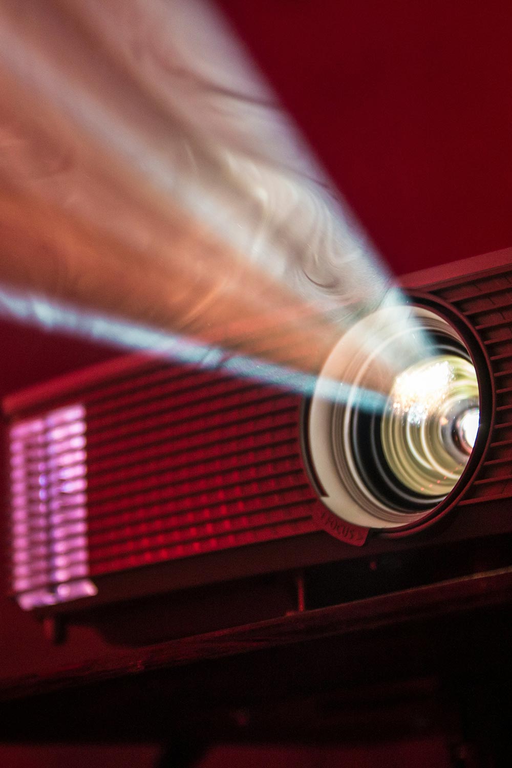Close-up of a projector lens emitting a bright beam of light in a dimly lit room