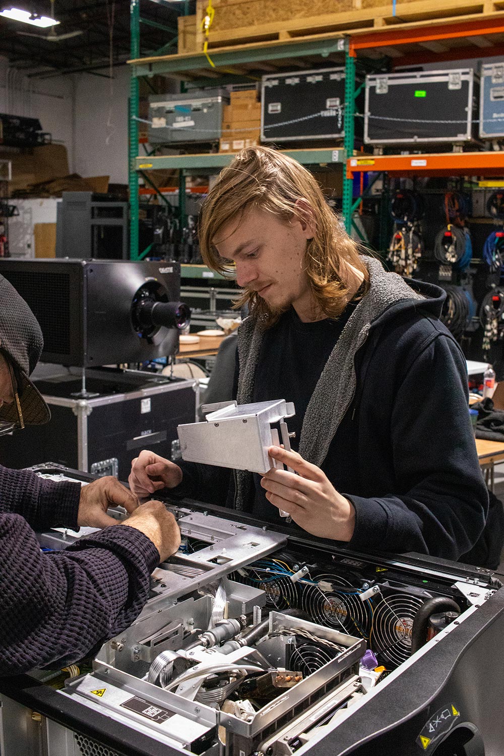 Young technician assisting with internal hardware installation in workshop setting