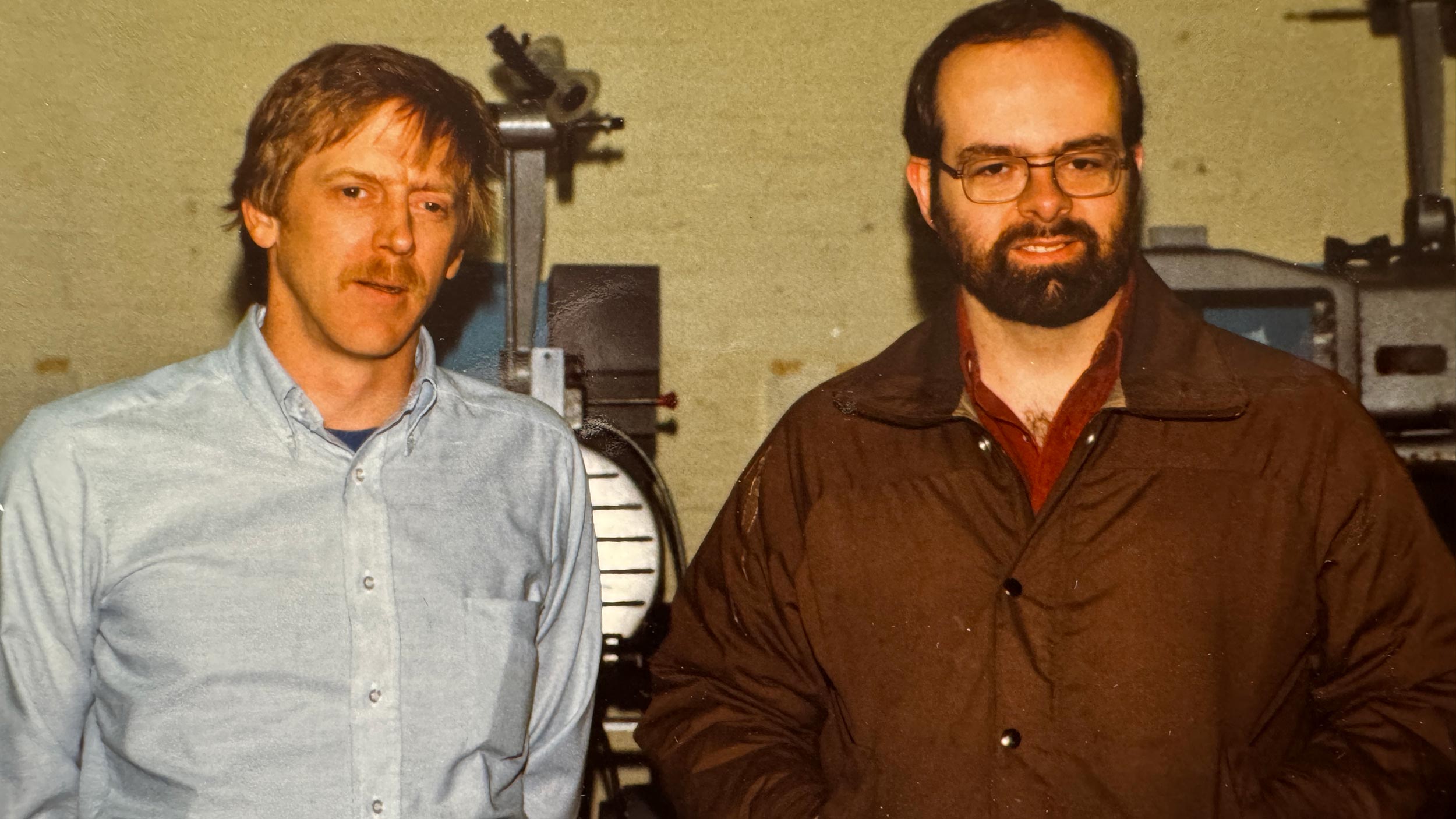 Two men standing in front of vintage film projection machinery