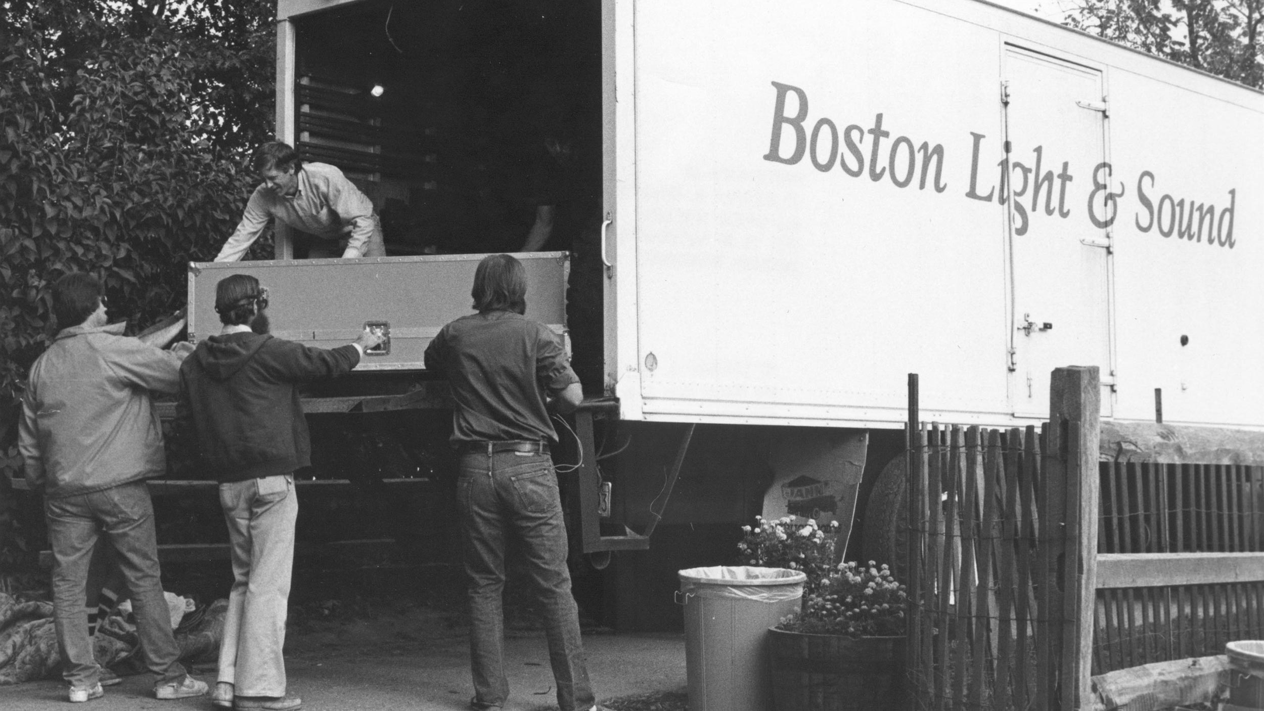 Crew loading equipment into a Boston Light & Sound truck from the rear platform