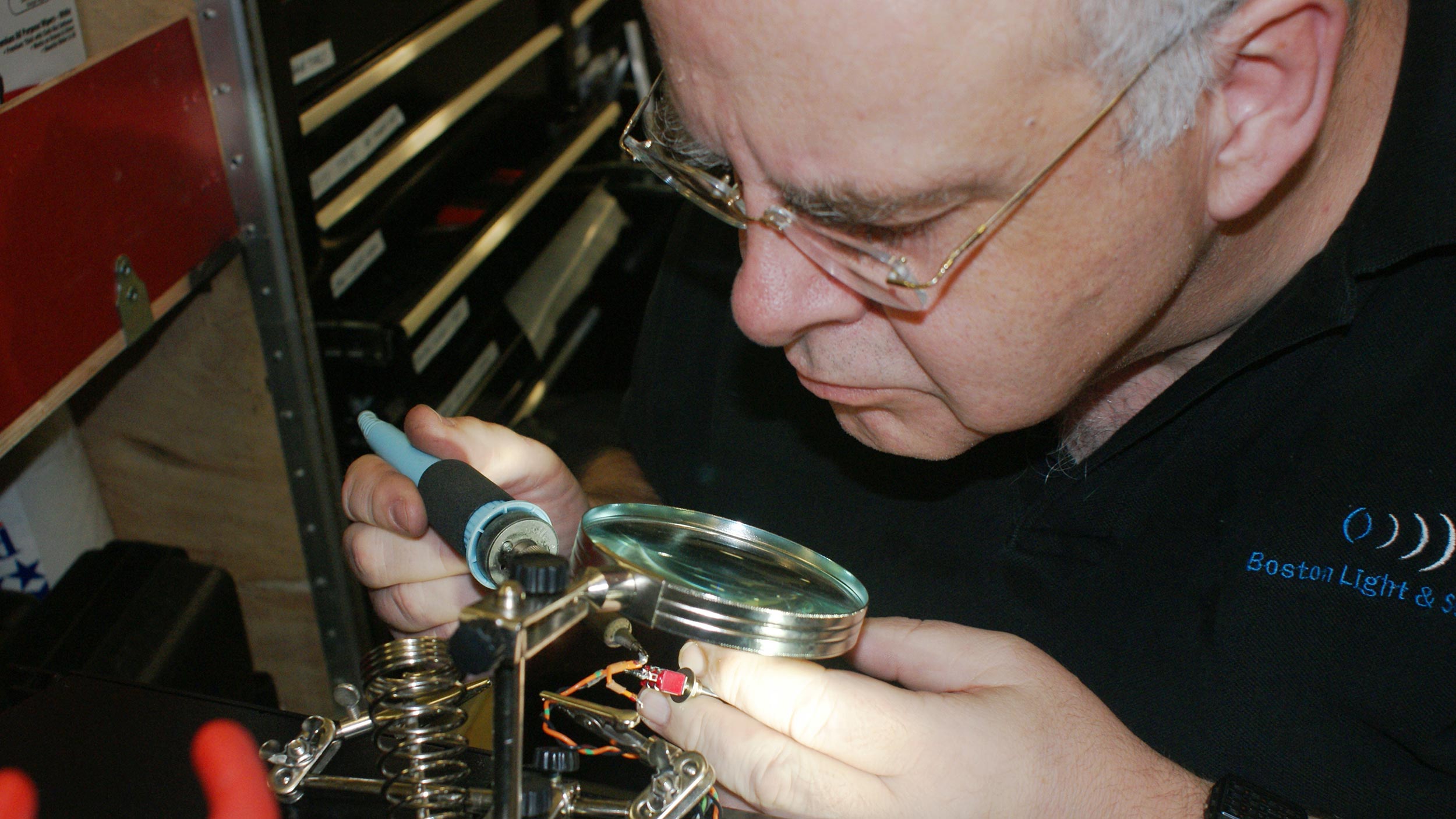 Technician soldering small electronics under magnifier