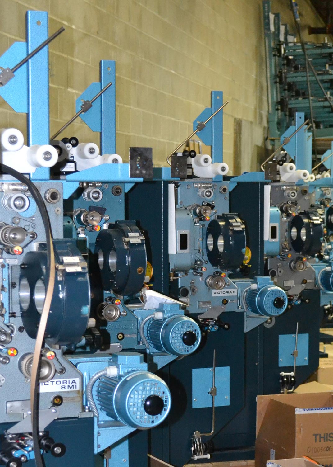 Row of vintage blue film projectors lined up in a storage area