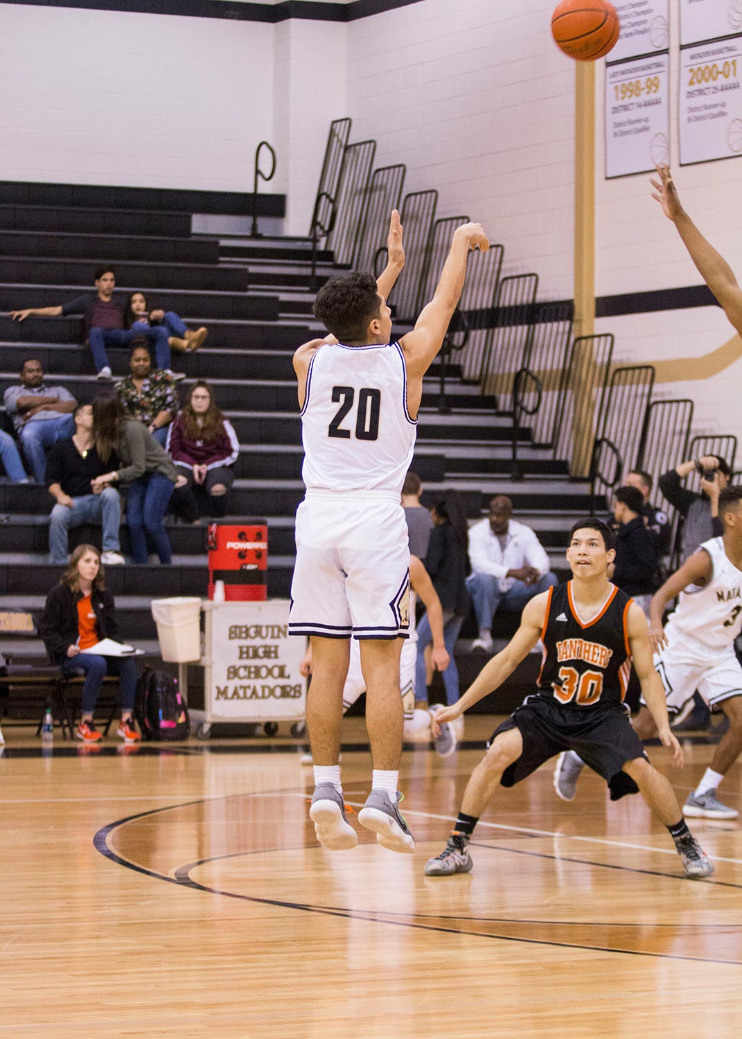 Basketball player in white jersey taking a jump shot during a game
