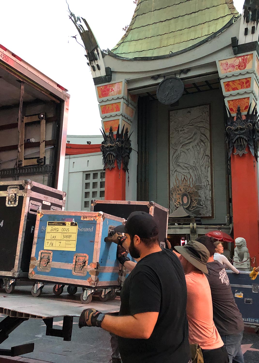 Crew unloading heavy equipment cases from a truck in front of a historic theater