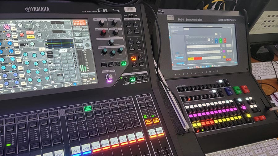 A close-up of a professional audio and event control system, featuring multiple screens, buttons, and knobs for managing live productions.
