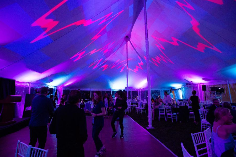 Party under a tent with purple and pink lights and people dancing