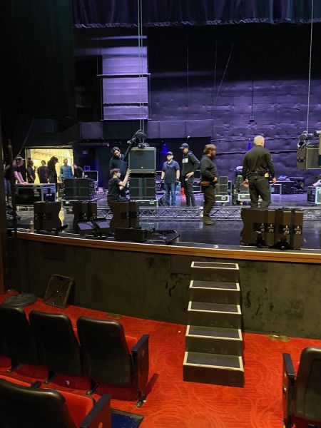 Crew preparing stage equipment in a theater with red carpet floor