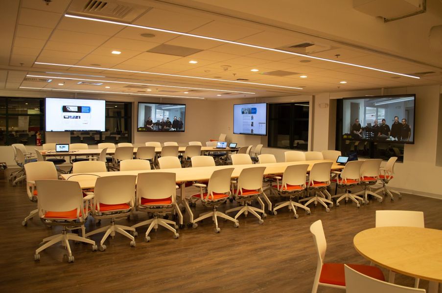 Technology-enabled learning space with video conferencing screens and tables