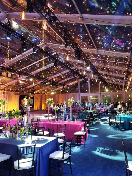 Event setup with colorful tables and string lights in a clear tent