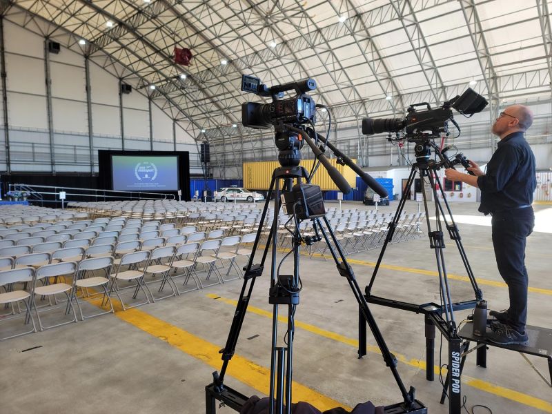 Cameraman filming empty chairs before a presentation in hangar venue