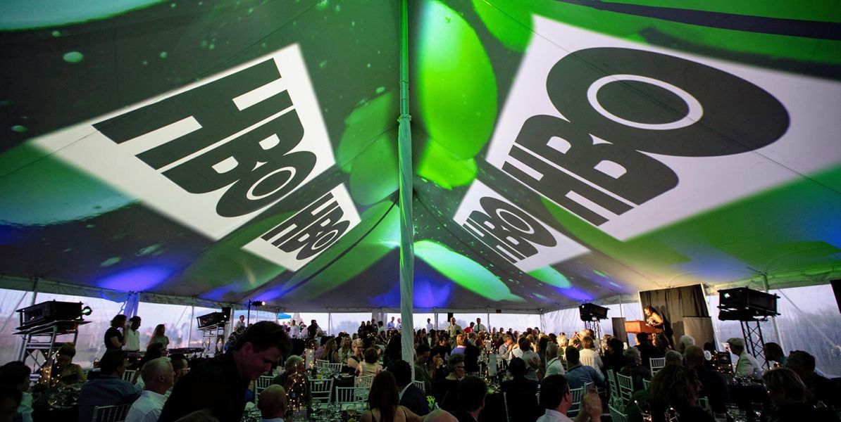 HBO-branded projection on tent ceiling during a formal dinner event