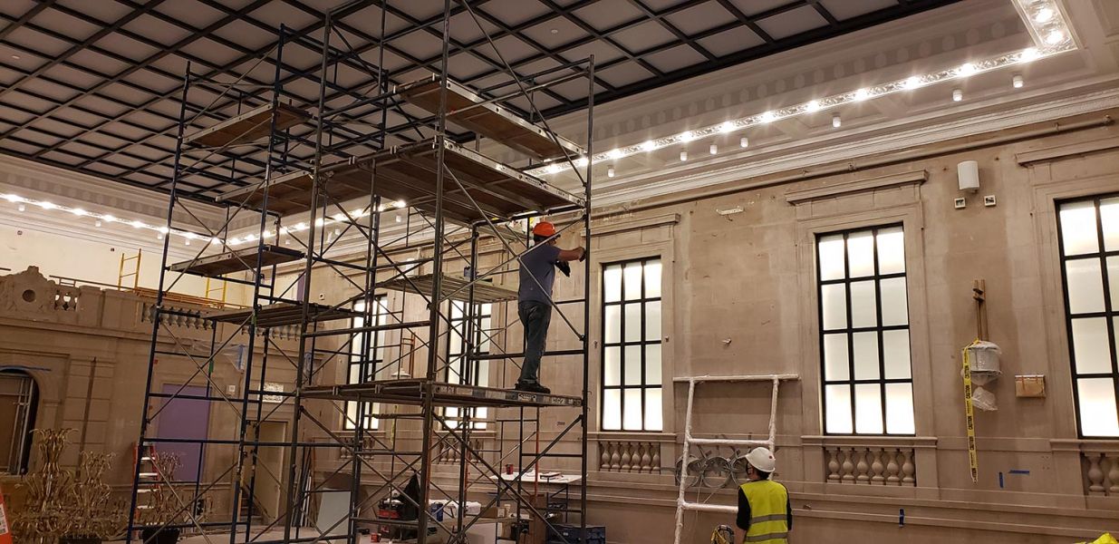 Wide view of ballroom under renovation with scaffolding and lighting work