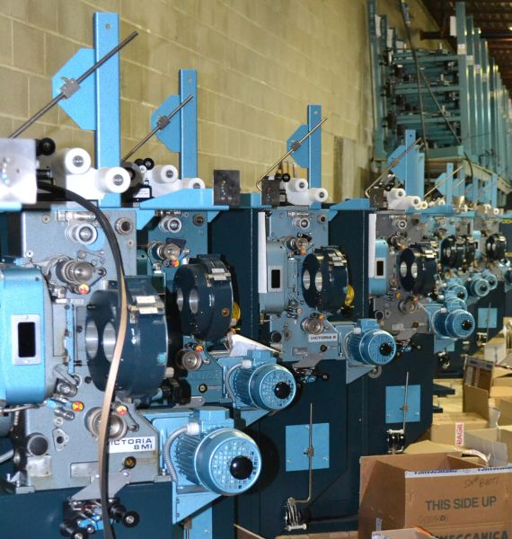 Multiple film projectors in storage with boxes stacked around them