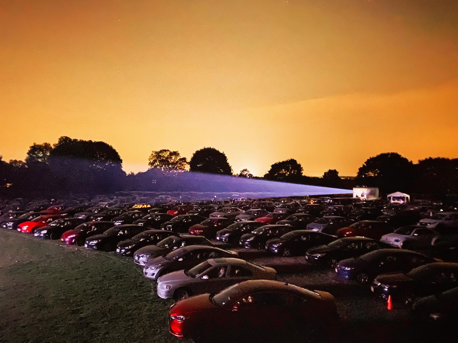 Beam of light from a projector illuminating a crowded drive-in theater