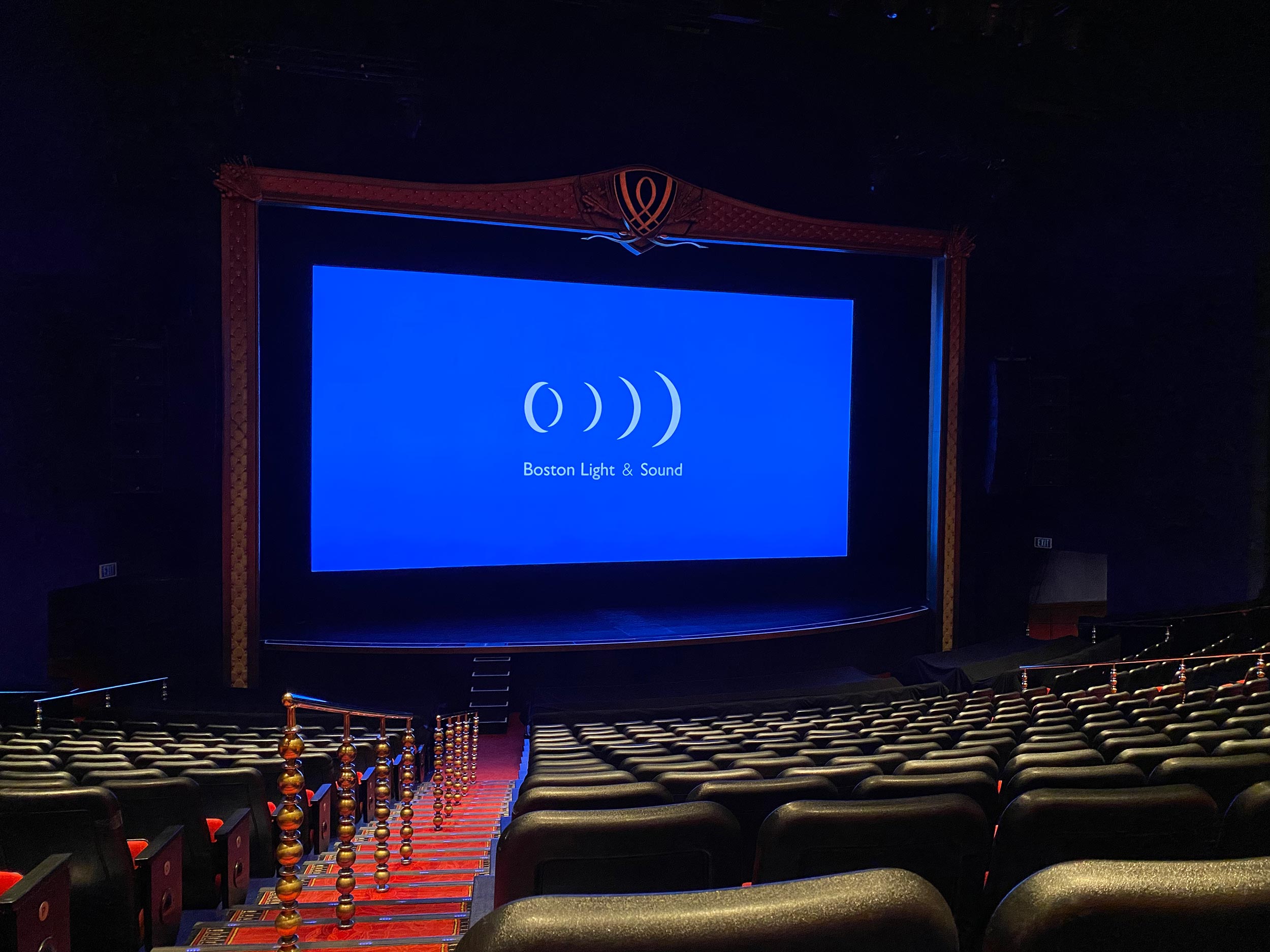 A large cinema screen displaying a blue background with white text in an empty movie theater.