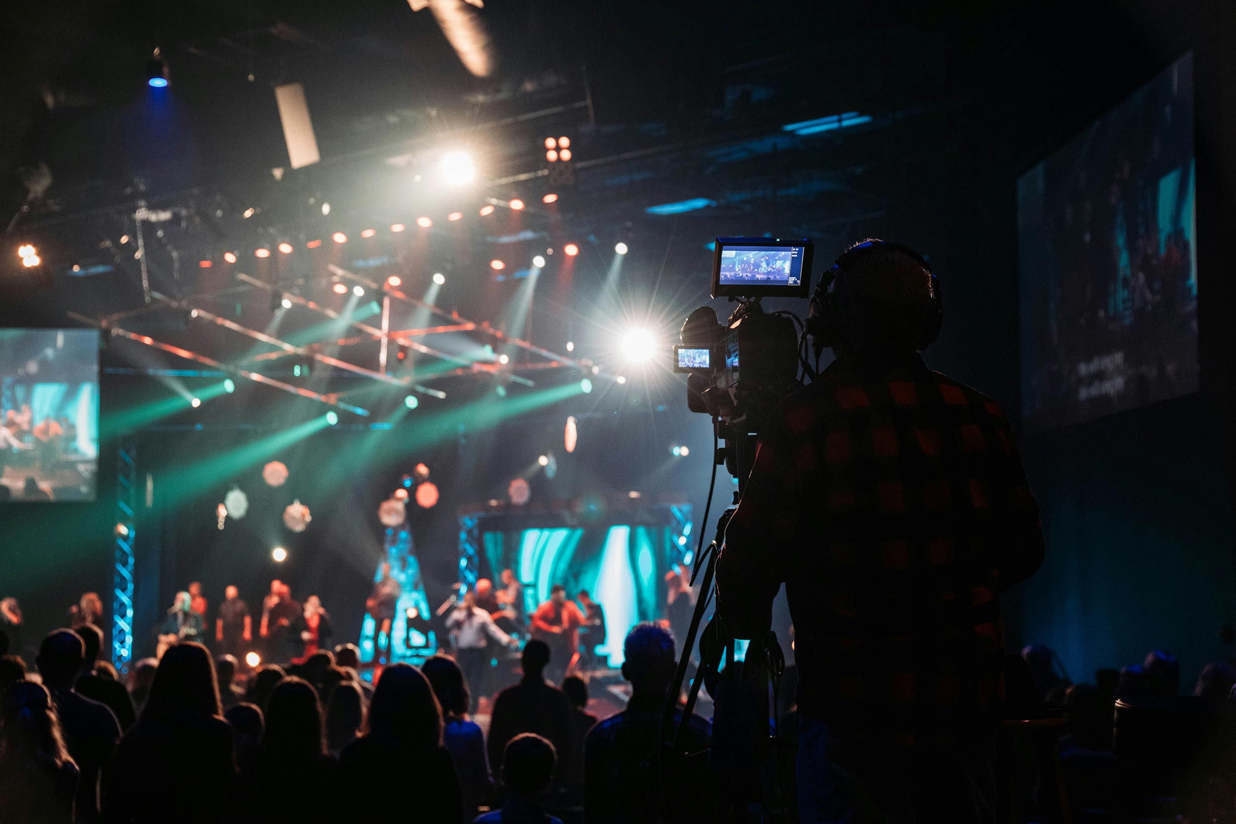 A concert production with a camera operator capturing a stage performance under colorful lighting.