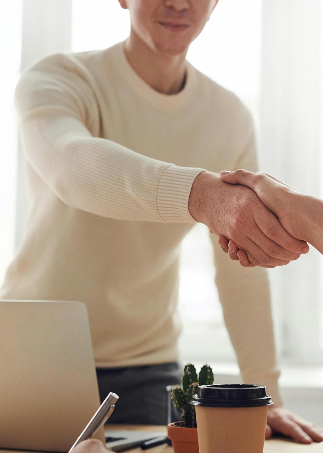 Two people shaking hands in a business setting.
