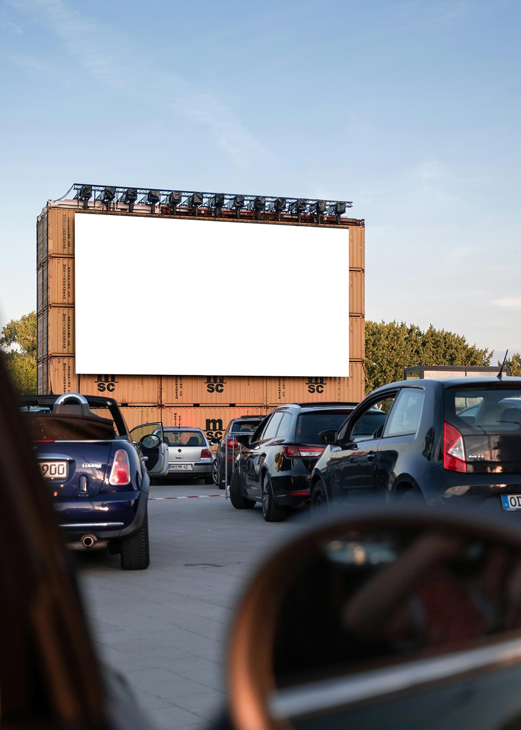A drive-in movie screen with parked cars in front, ready for a screening.