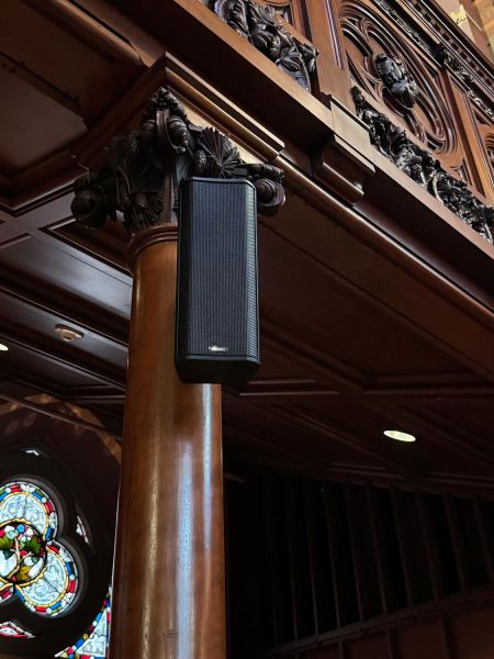 Column-mounted black speaker in an ornate wooden interior