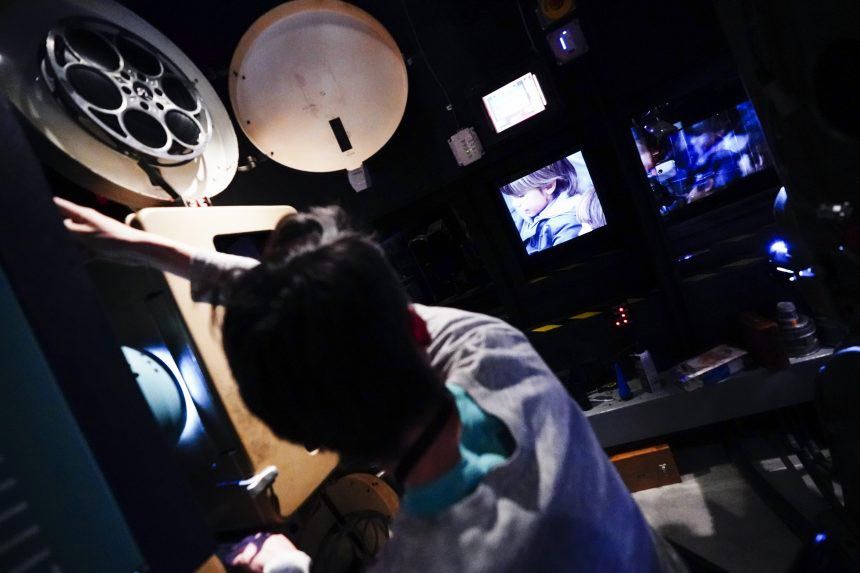 Projection booth with film reels and monitor showing scene in progress