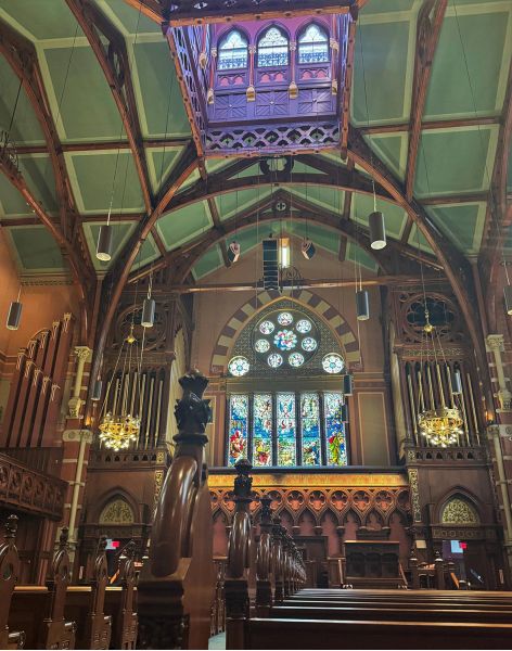 Church interior view showing stained glass window and ceiling-mounted speakers