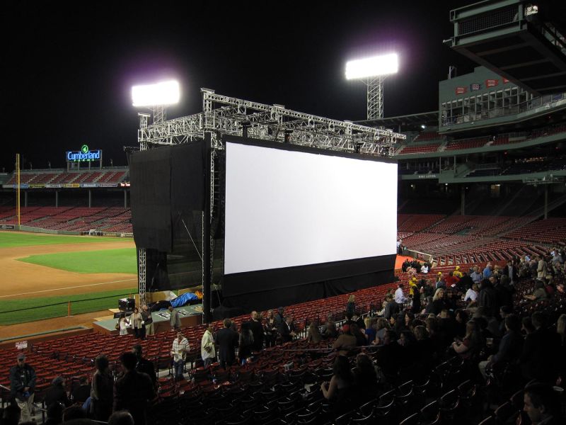 Outdoor movie screen setup at a baseball stadium at night