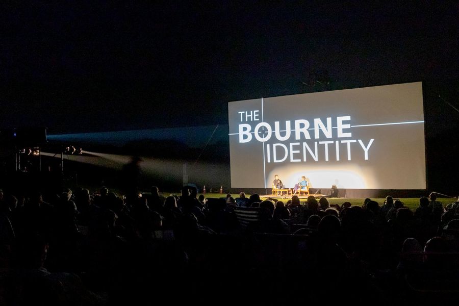 Outdoor screening of The Bourne Identity with audience watching and two speakers on stage
