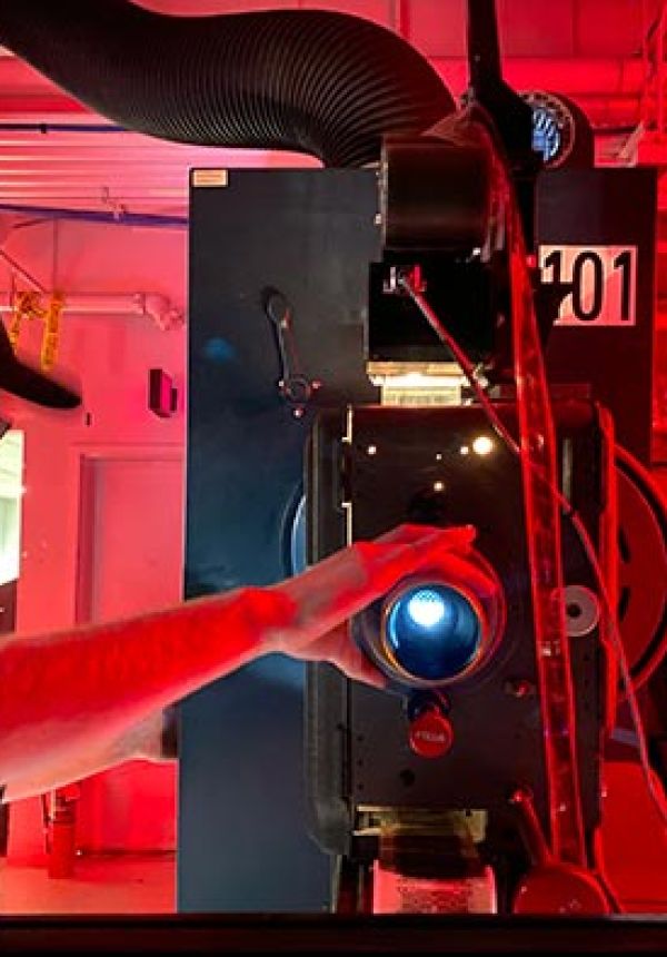 Technician adjusting a film projector in a room lit with red lighting